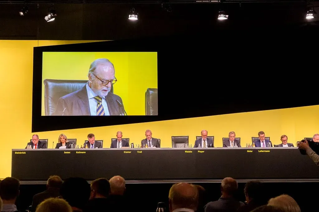 Foto von alten Männern auf einer Bühne bei einer AG-Hauptversammlung.